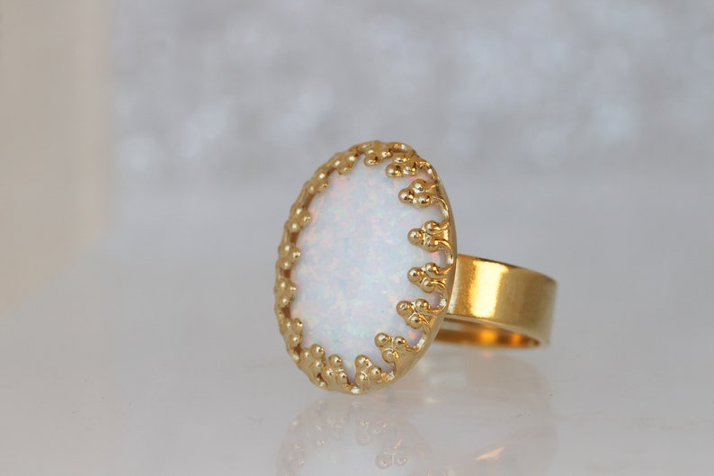 May include: A gold ring with a white opal stone set in a delicate, beaded design.