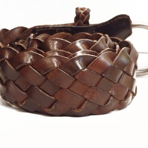 May include: A brown leather belt with a woven design and a silver buckle.