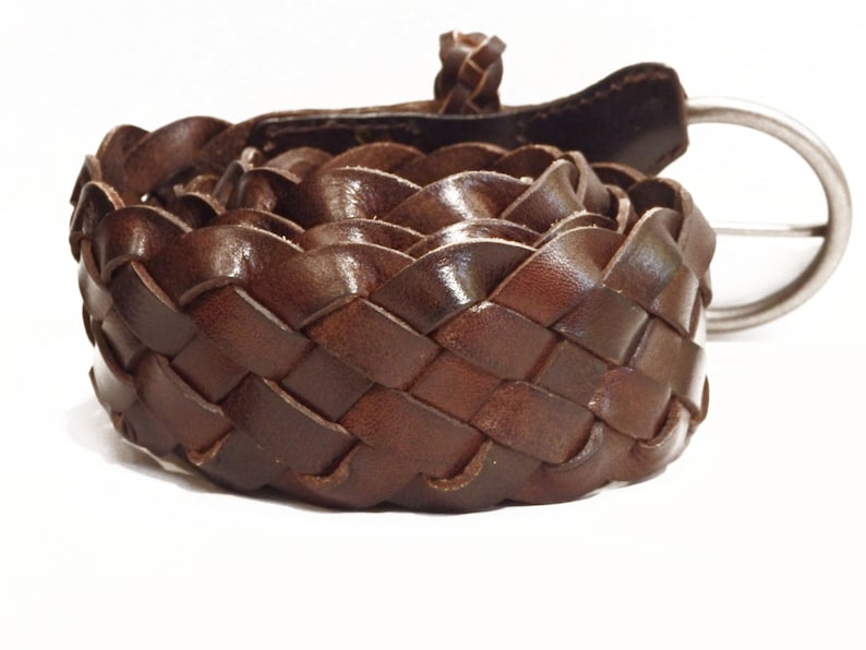 May include: A brown leather belt with a woven design and a silver buckle.