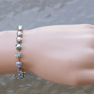 May include: A silver bracelet with a chain and iridescent rhinestones.
