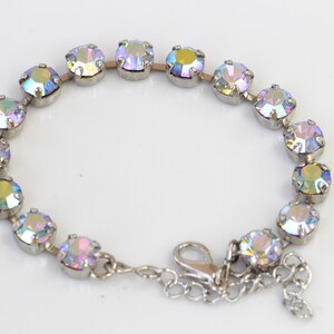 May include: A silver bracelet with iridescent round stones. The bracelet has a lobster clasp closure.