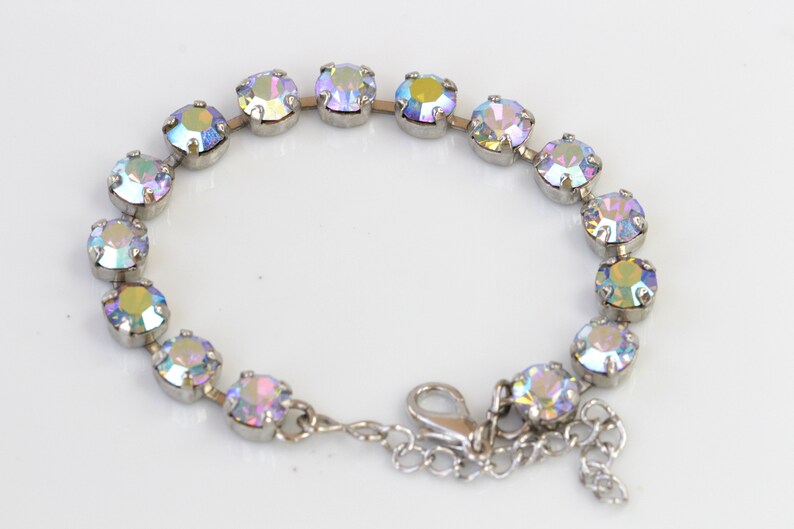 May include: A silver bracelet with iridescent round stones. The bracelet has a lobster clasp closure.