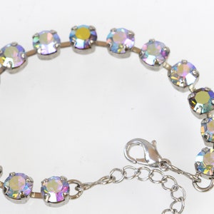 May include: A silver bracelet with iridescent round stones. The bracelet has a lobster clasp closure.