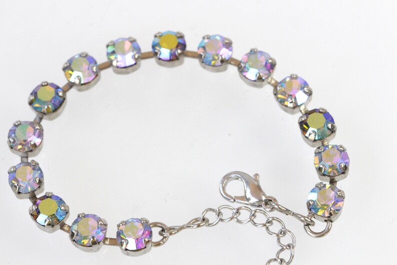 May include: A silver bracelet with iridescent round stones. The bracelet has a lobster clasp closure.