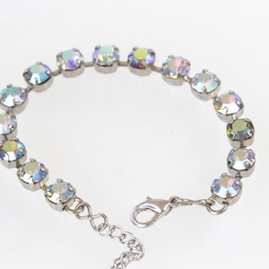 May include: A silver bracelet with iridescent crystals. The bracelet has a lobster clasp closure.