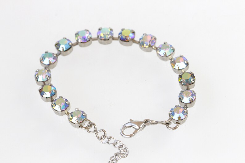 May include: A silver bracelet with iridescent crystals. The bracelet has a lobster clasp closure.