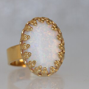 May include: A gold ring with a white opal stone set in a delicate, ornate design.