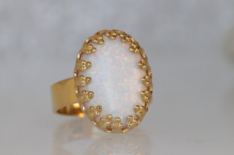 May include: A gold ring with a white opal stone set in a delicate, ornate design.