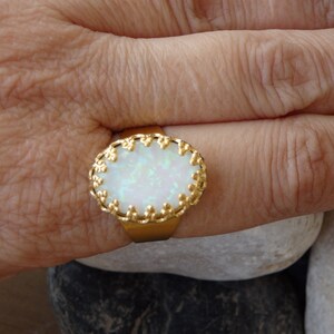 May include: A gold ring with a white opal stone set in a decorative gold frame.