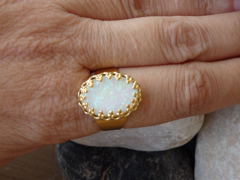 May include: A gold ring with a white opal stone set in a decorative gold frame.