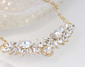 May include: A gold chain necklace with a large crystal pendant. The pendant is made up of many small, clear crystals arranged in a floral pattern.