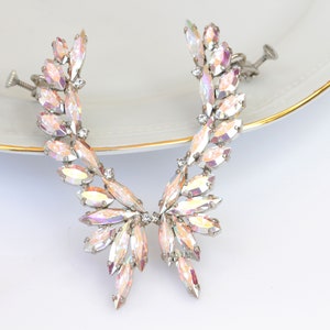 May include: A pair of iridescent crystal ear cuffs with silver metal settings. The cuffs are designed to clip onto the ear and feature a delicate, leaf-like design.