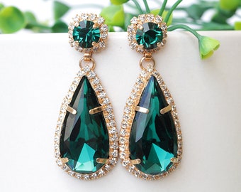 May include: A pair of emerald green teardrop earrings with gold settings and a halo of clear rhinestones.