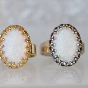 May include: Two oval rings with white opal stones set in ornate gold and silver settings.