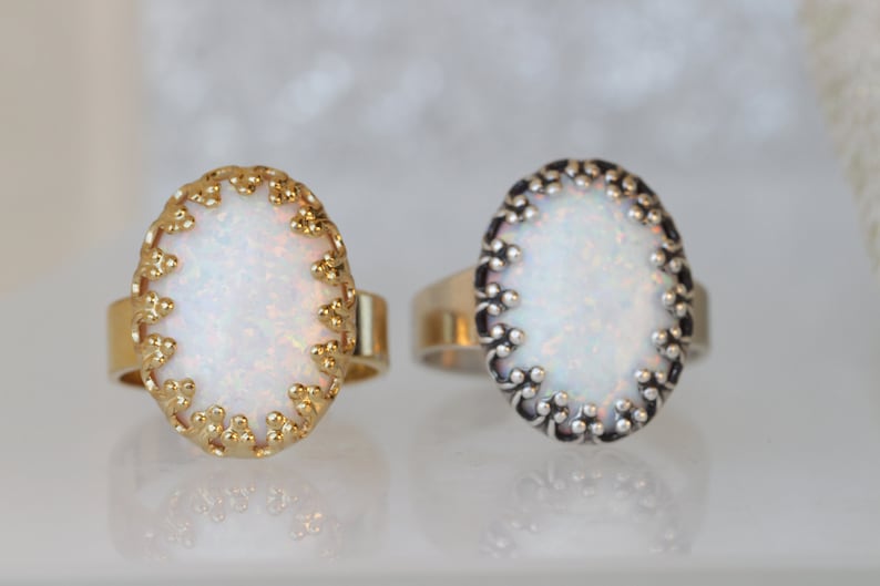 May include: Two oval rings with white opal stones set in ornate gold and silver settings.