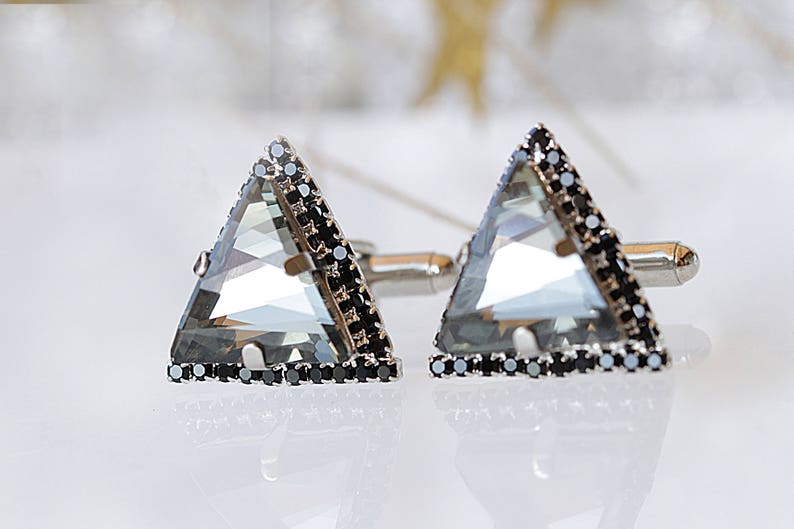 Puede incluir: Un par de gemelos de plata con un cristal transparente triangular engastado en un bisel negro.