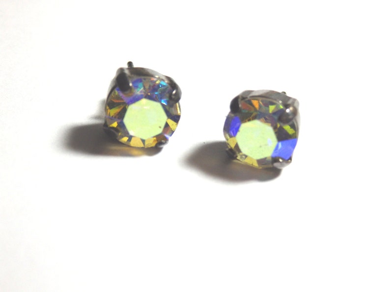 May include: A pair of iridescent yellow stud earrings with a silver setting.