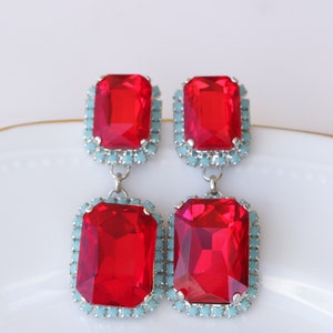 May include: A pair of dangle earrings with two large red rectangular stones set in silver with a border of light blue stones.