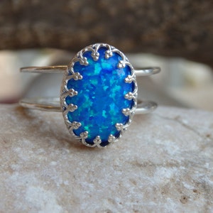 May include: A silver ring featuring a blue opal stone set in a delicate filigree design.
