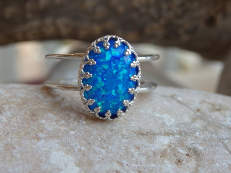 May include: A silver ring featuring a blue opal stone set in a delicate filigree design.