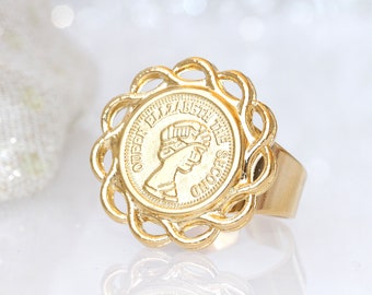 May include: Gold ring featuring a coin with the inscription "QUEEN ELIZABETH THE SECOND".