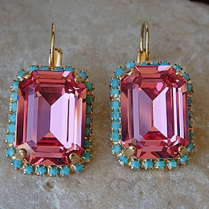 Puede incluir: Un par de pendientes de piedra rosa con borde turquesa y dorado.