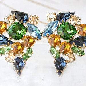 May include: A pair of gold tone earrings with a cluster of green, blue, and yellow rhinestones.