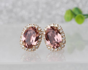 Puede incluir: Un par de pendientes ovalados con una piedra preciosa de color rosa rodeada por un halo de brillantes transparentes.