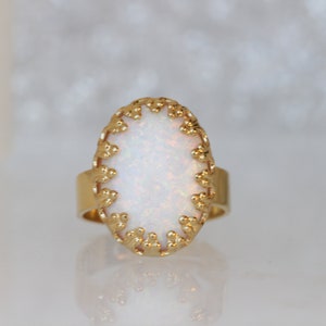 May include: A gold ring with a white opal stone set in a delicate, ornate design.