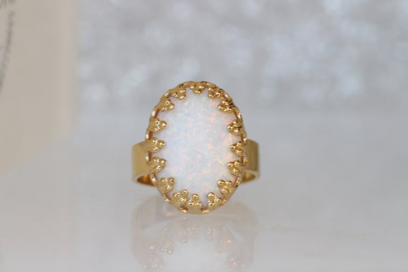 May include: A gold ring with a white opal stone set in a delicate, ornate design.