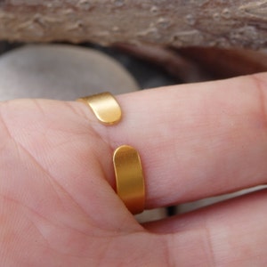 May include: Gold adjustable ring with a smooth, rounded band. The ring is open in the back and can be adjusted to fit different finger sizes.