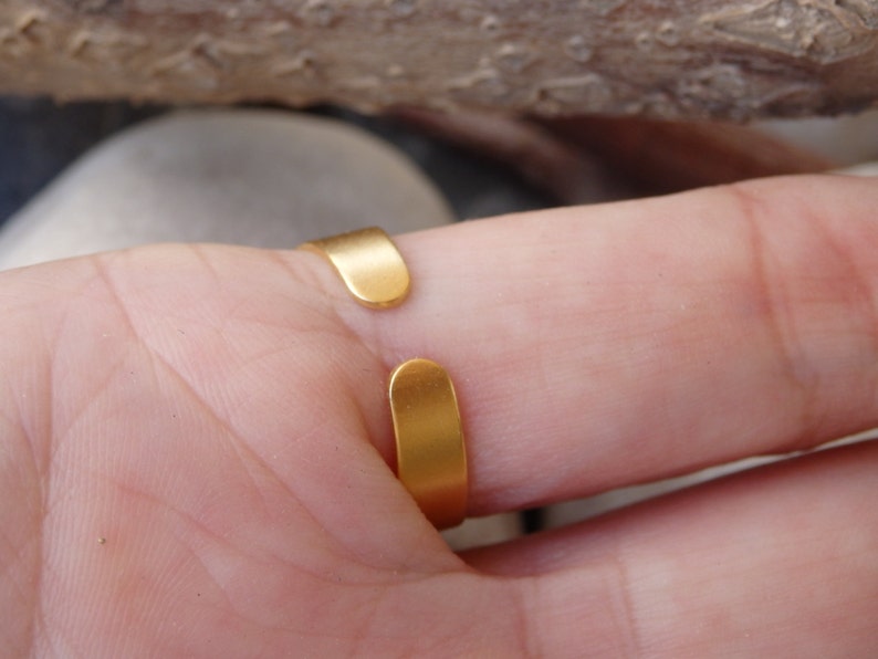 May include: Gold adjustable ring with a smooth, rounded band. The ring is open in the back and can be adjusted to fit different finger sizes.