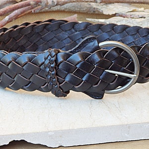 May include: A dark brown leather belt with a braided design and a silver buckle.