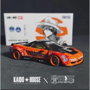 May include: A miniature orange and red Honda sports car with black detailing, featuring the word "AACE". The model car has a "HONDA" logo and is a collaboration between "KAIDO HOUSE" and "ONE PIECE".
