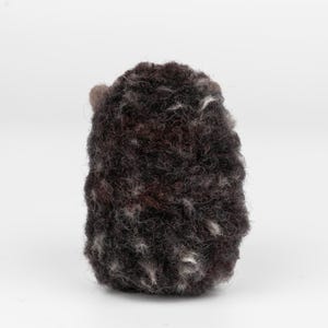 May include: A handmade, dark brown felted wool hedgehog figurine with gray and white flecks. The hedgehog has small, rounded ears and a textured, spiky appearance. The craft item is set against a plain white background.