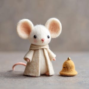 May include: A handcrafted felt mouse figurine with large, light pink-lined ears, wearing a beige coat and scarf. A small, golden bell with a gold bead on top sits beside the mouse. The mouse has a pink nose and a long, pink tail.