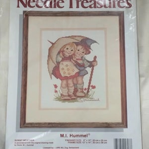 May include: A cross-stitch kit titled "Needle Treasures" featuring a framed image of two children under an umbrella. The image is a cross-stitch design by M.I. Hummel, with a finished size of 8" x 10" (20 cm x 25 cm). The kit includes charted design, floss, and instructions.
