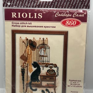 May include: A RIOLIS cross stitch kit 860 in a clear plastic package. The kit features a finished design of a black cat, a birdcage, a rotary telephone, a hat, and a coat rack. The finished size is 7 inches by 9.5 inches or 18 cm by 24 cm.
