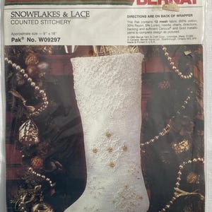 May include: A packaged counted stitchery kit for a Christmas stocking. The kit includes a white stocking with snowflake and lace designs, measuring approximately 9" x 18". The package is labeled "Snowflakes & Lace" and "Pak No. W09297".