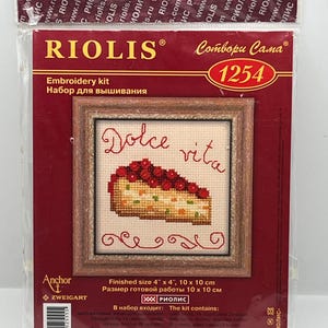 May include: RIOLIS embroidery kit featuring a cross-stitch design of a cake slice with the words "Dolce vita." The finished size is 4" x 4". The kit includes Anchor and Zweigart materials. The packaging is red and brown.