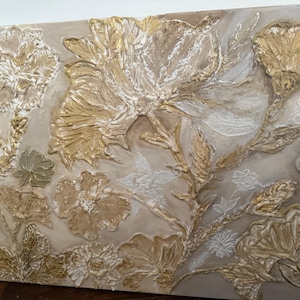 Peut inclure: Une œuvre d'art florale texturée avec des fleurs en relief en trois dimensions dans des tons or, blanc et beige. L'œuvre a un fond neutre et est une pièce décorative pour la décoration intérieure.
