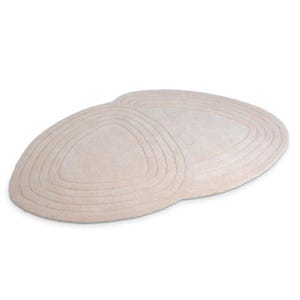 May include: A beige, oval rug with a soft, textured surface. The rug features concentric, curved lines, creating a subtle geometric pattern. The rug is designed for floor placement. The measurements are in centimetres.