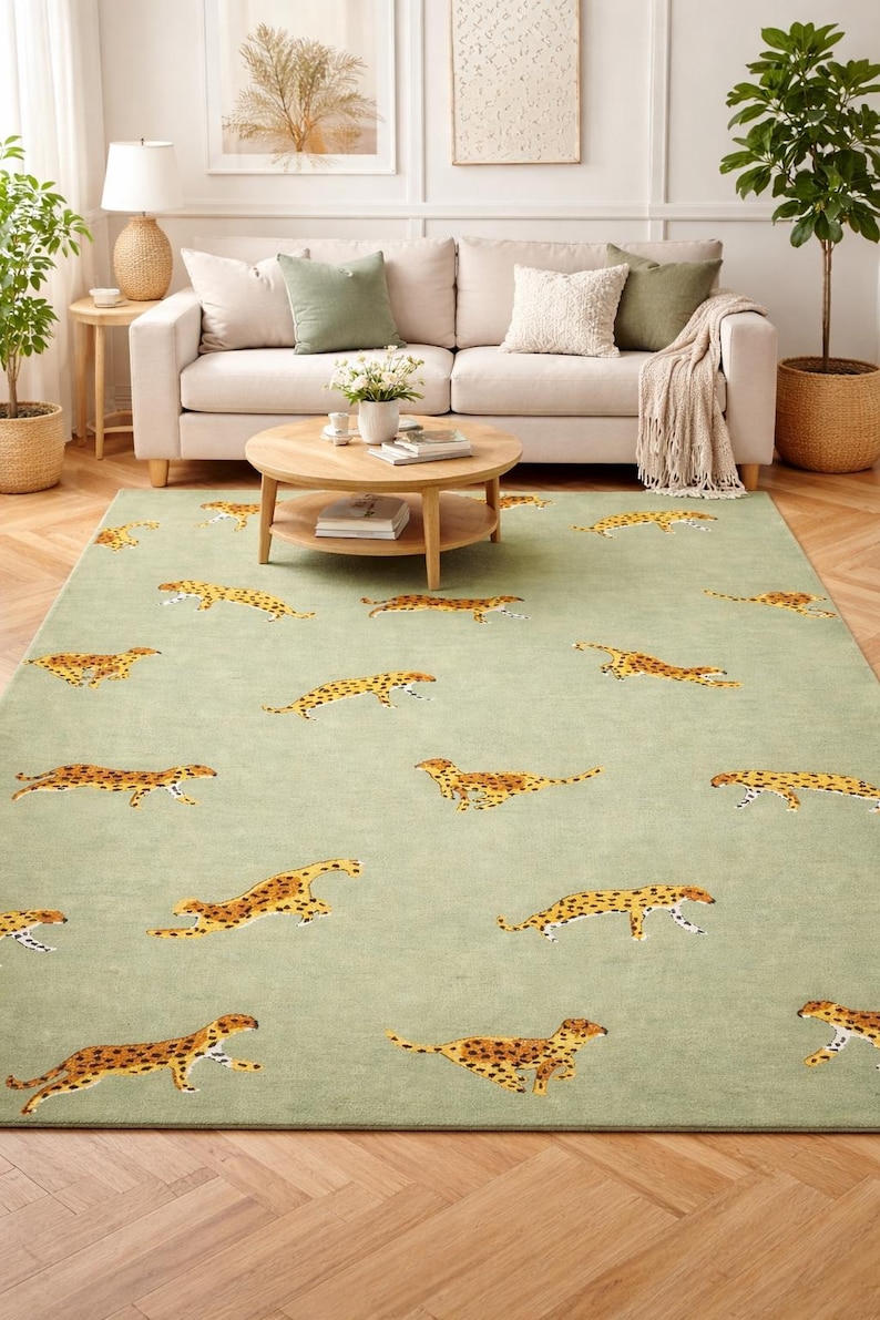 May include: A rectangular area rug in a light green hue, adorned with multiple cheetah illustrations in shades of brown and yellow. The rug is placed in a living room setting, with a sofa and coffee table.