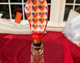 Tapón de vino artesanal con diseño de conchas marinas y pequeñas banderas de corazón de estilo americano.