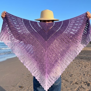 Peut inclure: Un châle triangulaire au crochet présentant un dégradé de couleurs allant d'un violet foncé profond au centre supérieur à un lavande pâle et clair sur le bord inférieur pointu, avec un motif complexe de dentelle ajourée.