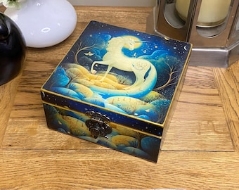 Caja cuadrada de madera decorada a mano en estilo decoupage. Diseño de unicornio encantado en azul, dorado y blanco.