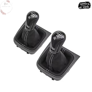 May include: A white ceramic mug with a black handle and the text "But First, Coffee" in a bold, black font. The mug is set against a blurred background, suggesting a cozy setting.