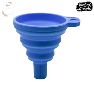 May include: A blue, collapsible silicone funnel. The funnel has a wide mouth, a ridged body, and a small spout. The handle has a small hole for hanging. The words "hand made" are in a black circle.