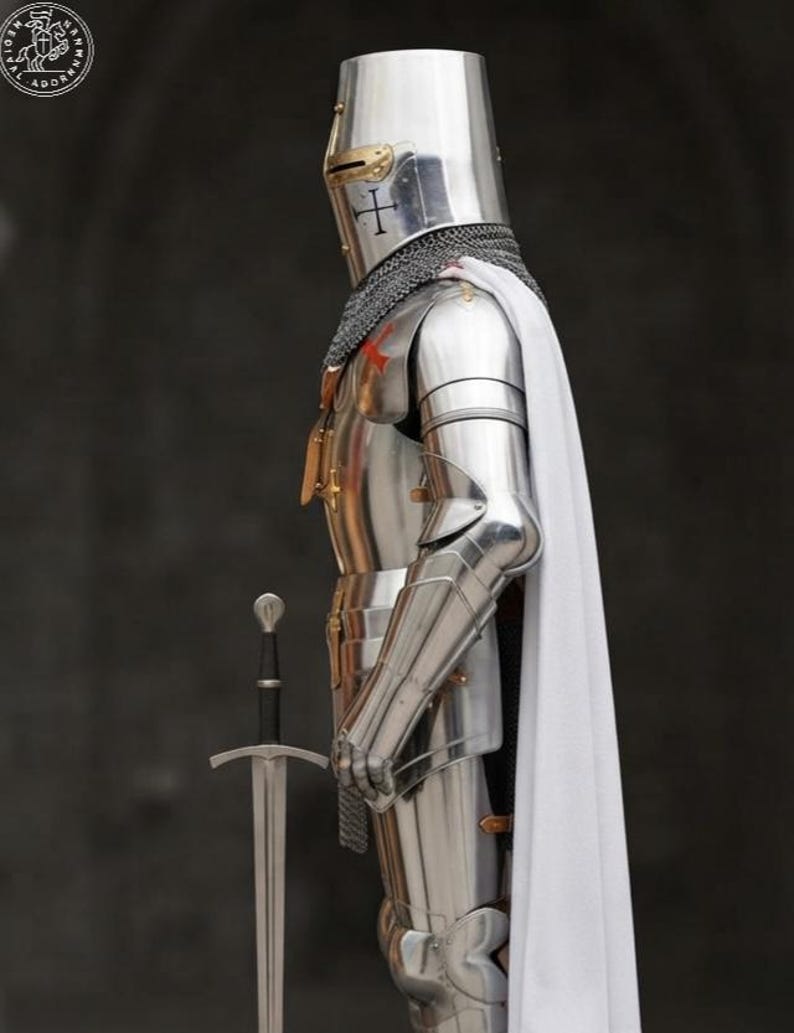 K&ouml;nnte beinhalten: Eine vollst&auml;ndige R&uuml;stung aus poliertem Stahlblech mit einem flachen Helm mit goldfarbenem Visier, einer Kettenhaube und einem langen wei&szlig;en Umhang. Die R&uuml;stung umfasst bewegliche Arm- und Beinteile, und ein Stahlschwert steht aufrecht daneben.