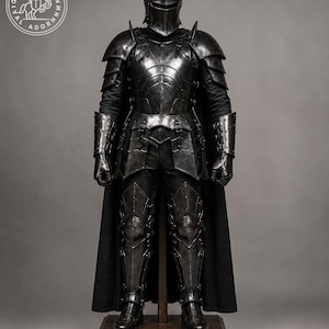May include: A full suit of dark charcoal metal armor featuring a rounded helmet, articulated shoulder pauldrons, gauntlets, and greaves. The armor is worn over a black garment with a long black cape. A circular logo with a horse is in the top left.